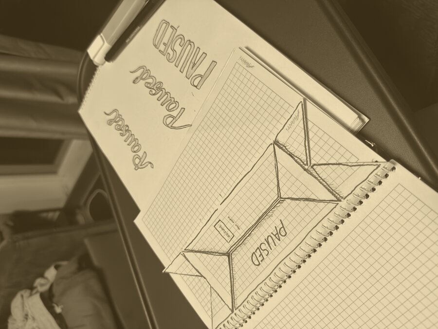 A pad of pause-screen lettering studies beside the folded-paper sketch of the fold.